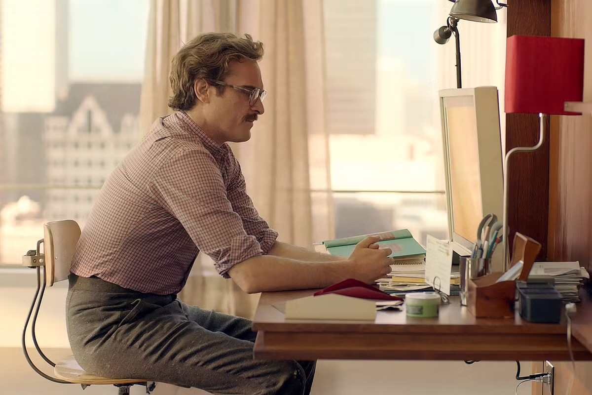 Theodore Twombly seated at his desk facing the Samantha OS screen, from the film Her (Spike Jonze, 2013)